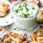 Onion latkes surrounding bowl of chive sour cream.