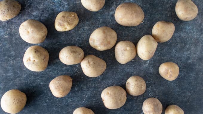 Washed whole potatoes on dark background.