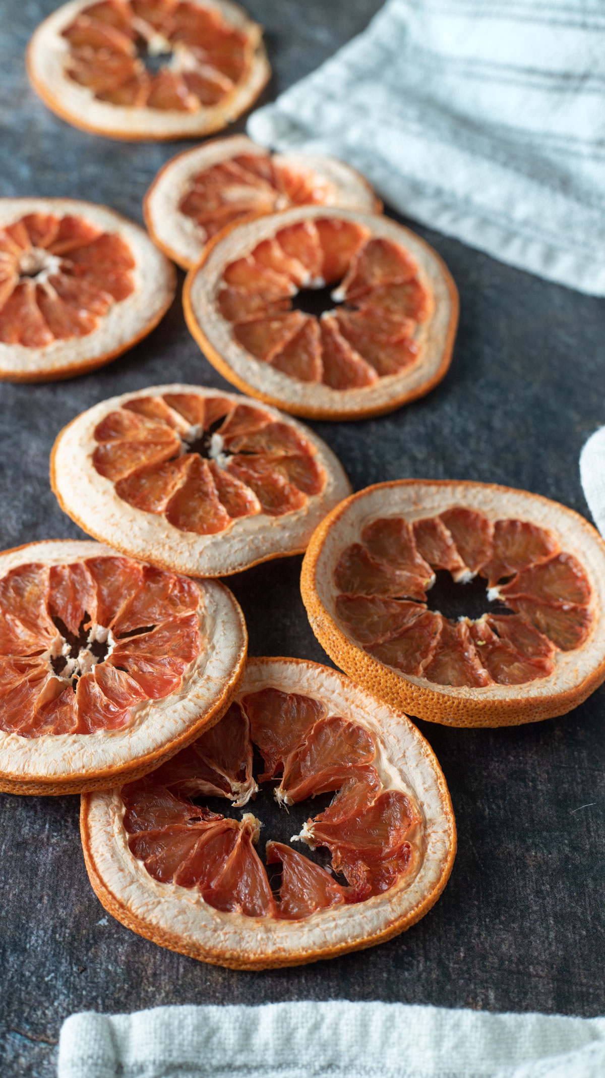 Dried grapefruit on a dark background with white tea towel.