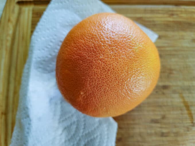 Whole washed grapefruit on cutting board. 