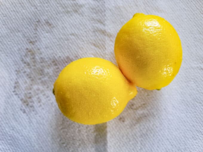 Two whole lemons on paper towel.
