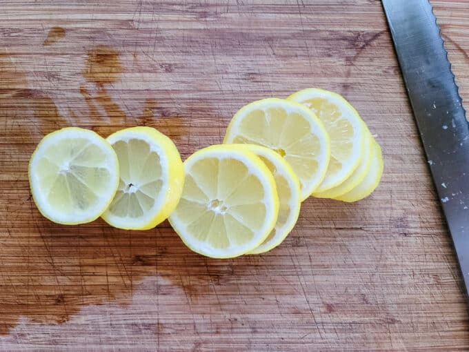 Sliced lemons on board with serrated knife.