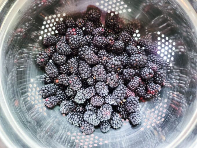 Blackberries in a metal colander.
