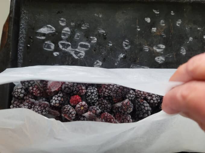Grabbing the ends of the parchment paper to pour berries into bags. 