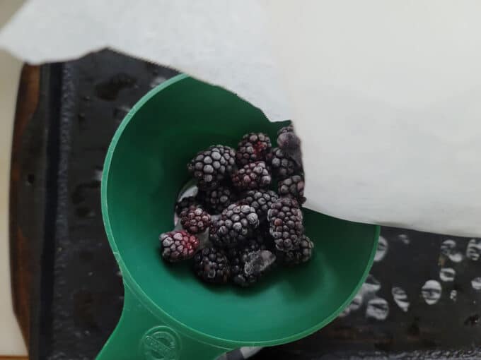 Pouring berries into canning funnel.