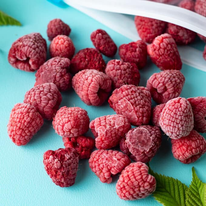 Frozen raspberries on teal board.
