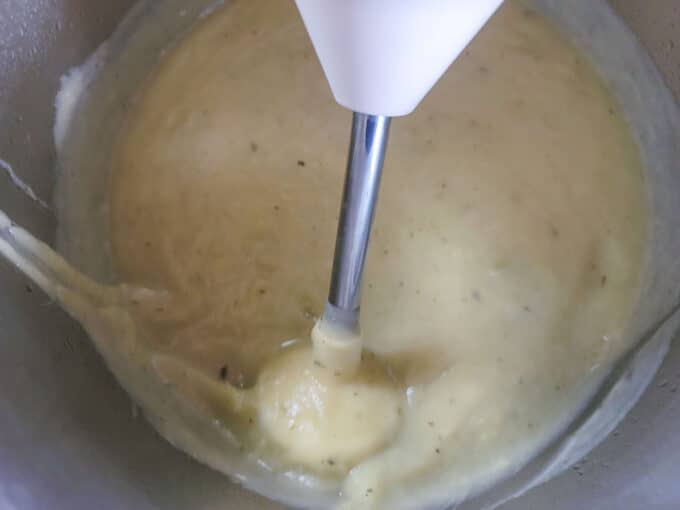 Pureed soup with blender in pot.