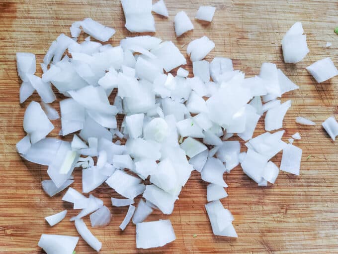 Rough chopped onion on board.