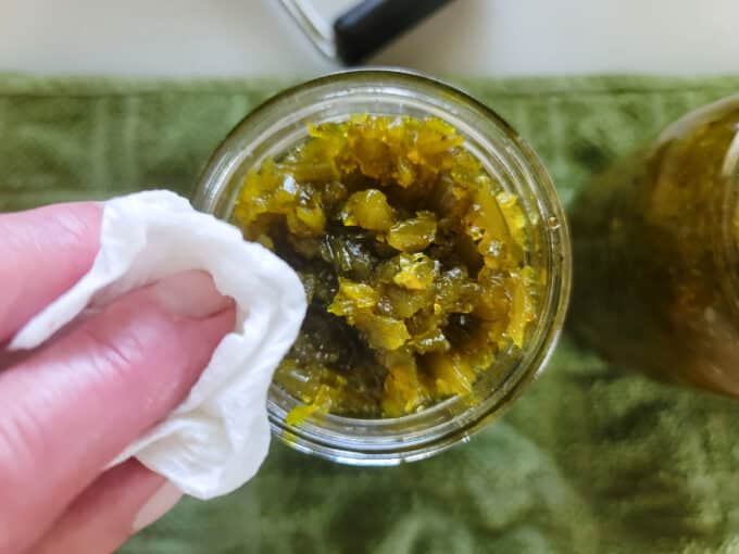 Woman's hand wiping rims of jars.
