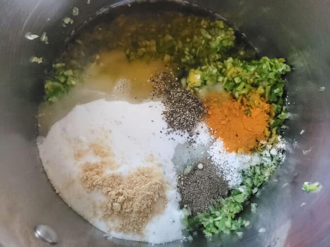 Spices added to the vegetables in a large pot.