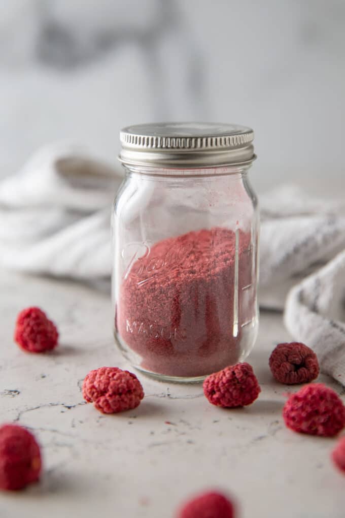 Small jar of raspberry powder with dried raspberries.