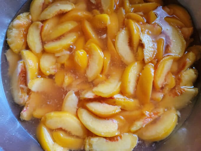 Peeled peaches in bowl with ascorbic acid.
