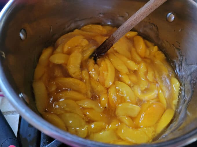 Peaches mixed with pie filling base in pot.