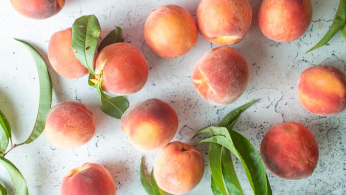 Fresh peaches on a white board.