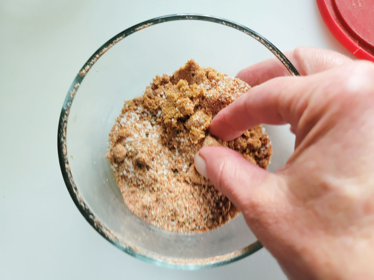 Breakinf up clumps of brown sugar with fingers.