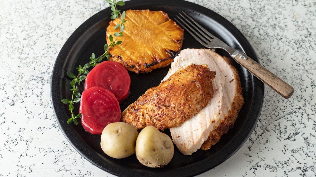 Smoked whole chicken full meal on black plate.