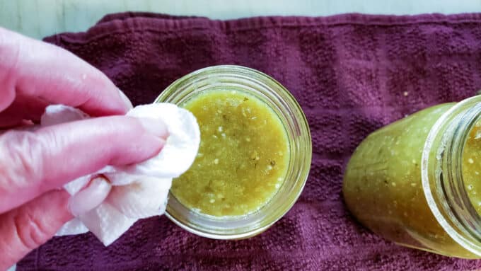 Wiping rim of jar with damp paper towel.