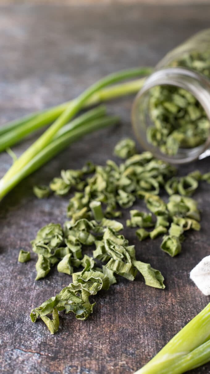 Dried green onions spilling out of jar.
