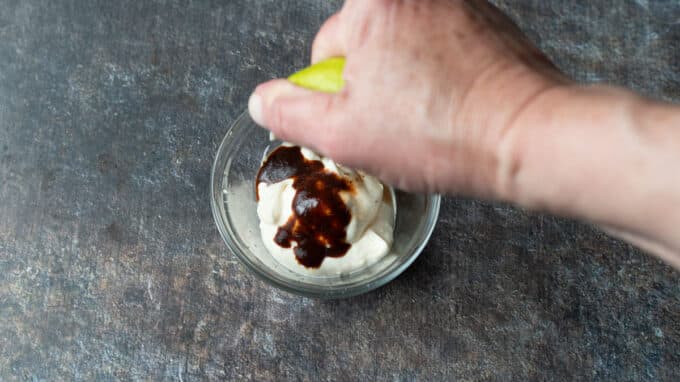 Hand squeezing lime juice into bowl.