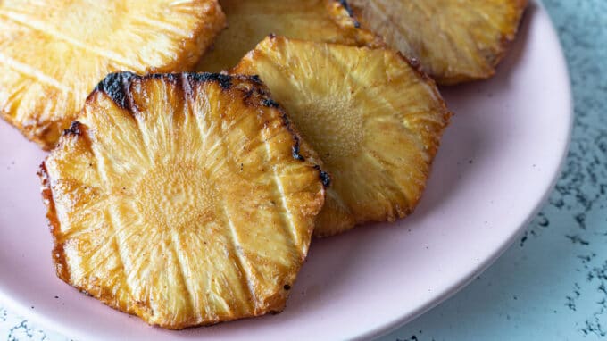 Close up of pineapple on pink plate.