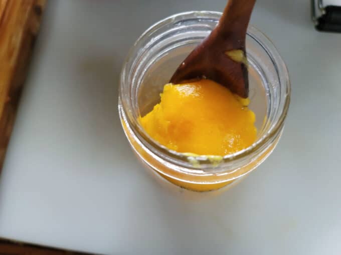 Using a spoon to turn peach in jar over.