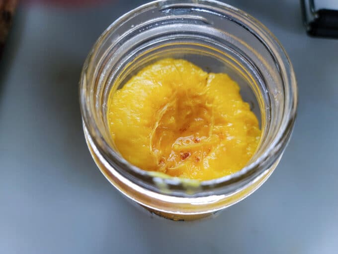 Peach in jar with cut side up.