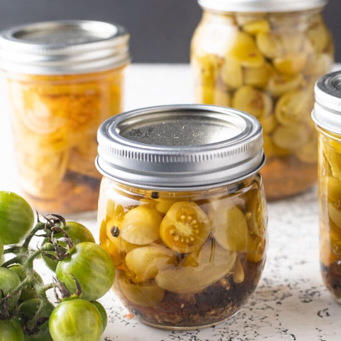 Close up of jars of pickled green tomatoes.