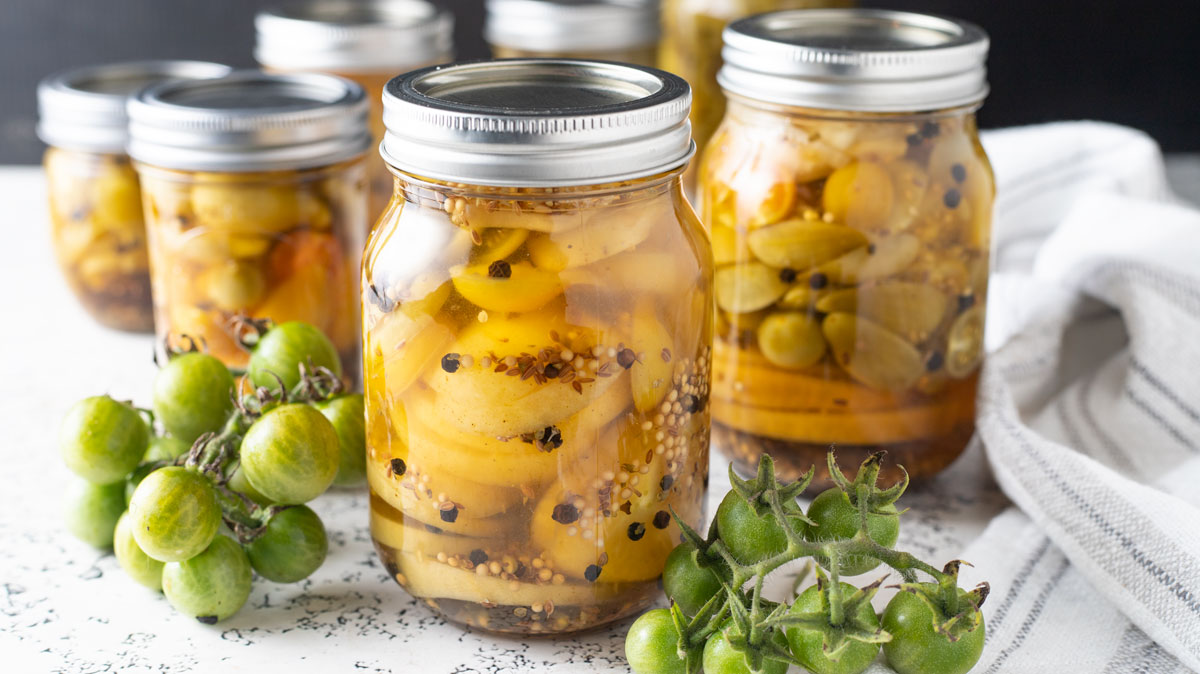 Sliced green tomato pickles in jars.