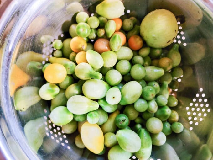 Washed green tomatoes in colander.