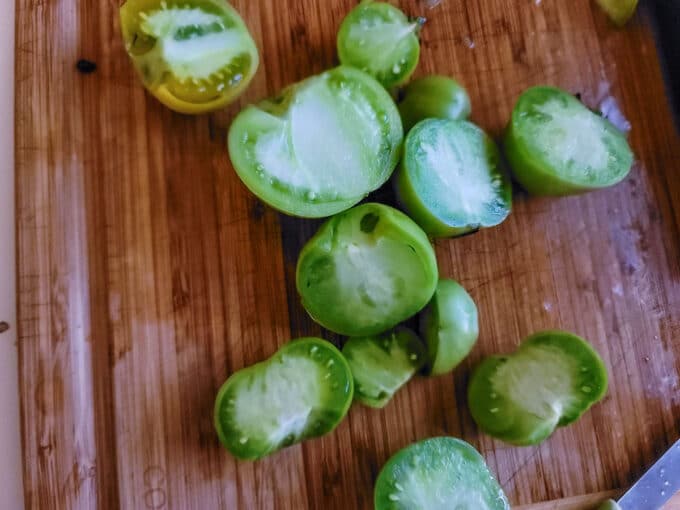 Halved green tomatoes on board.