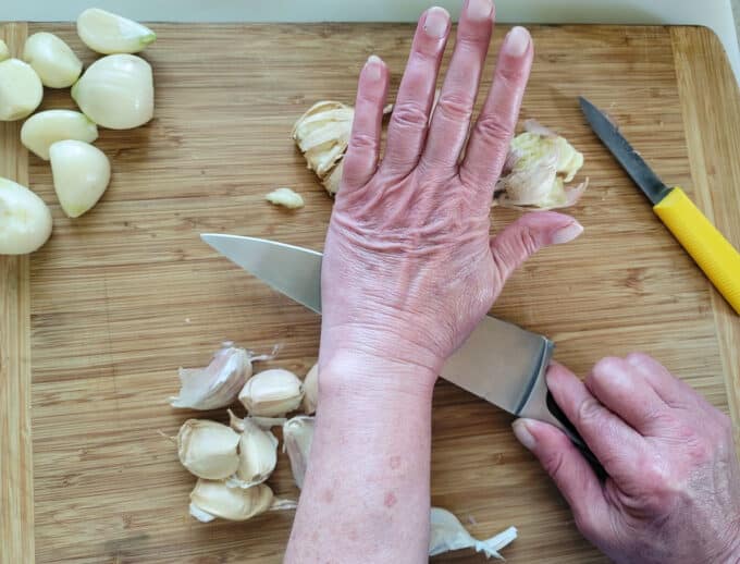 Woman's hand smashing garlic clove.