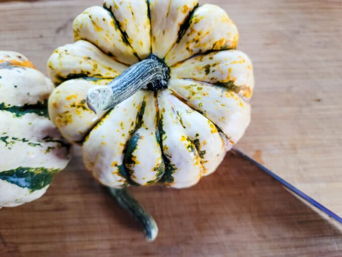 Knife slicing through the first side of the squash.