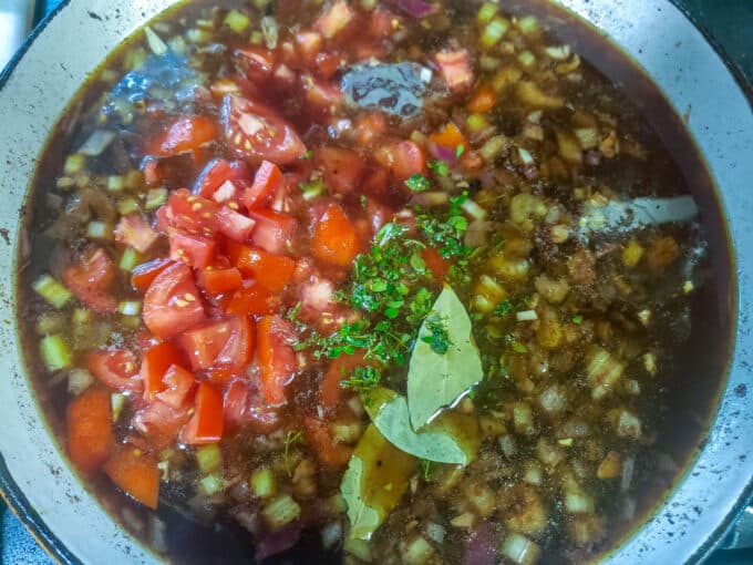 Stock, tomatoes and herbs added to pan.