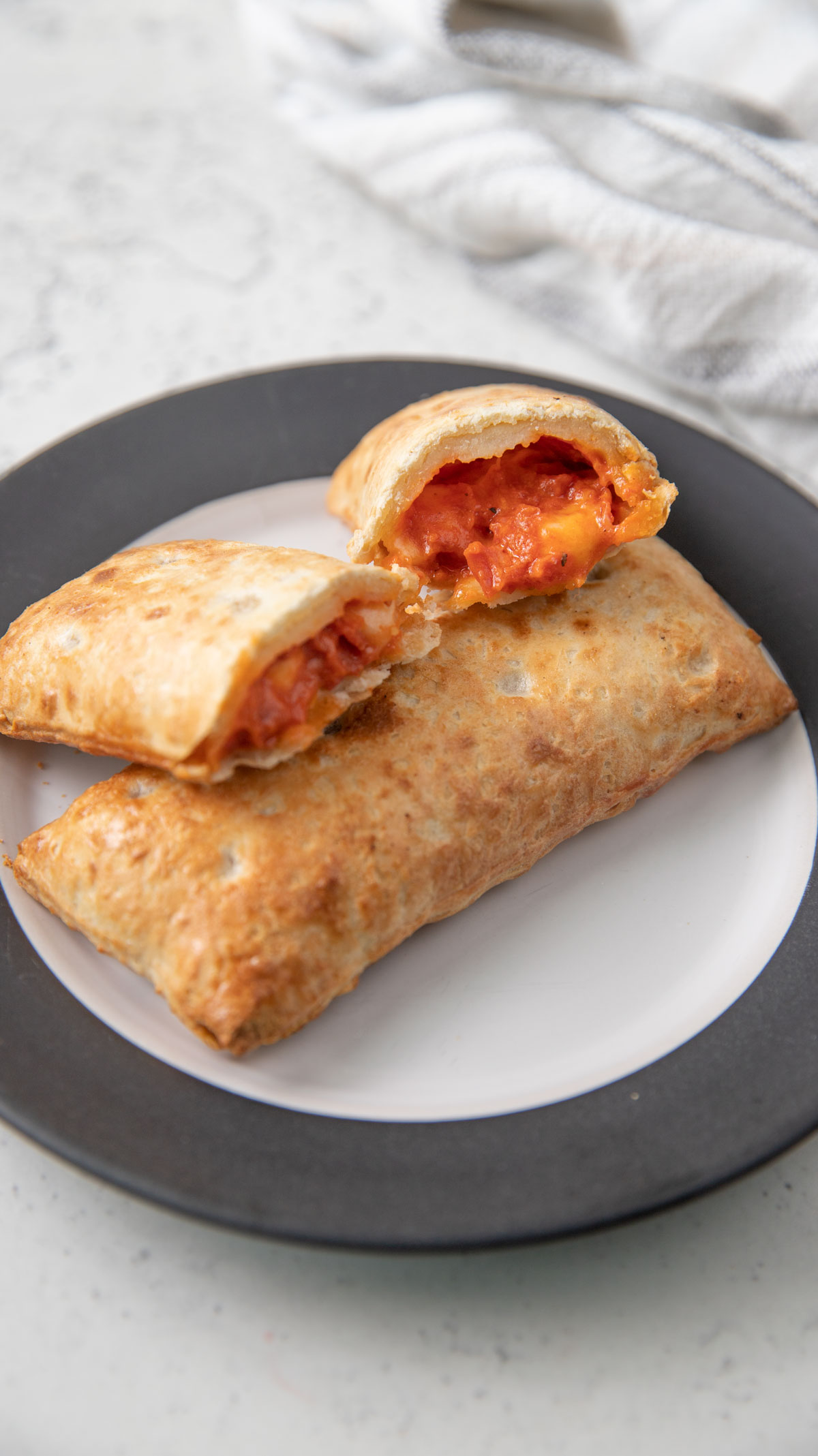 Two hot pockets on a white plate with black trim.