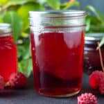 Dogwood Jelly in jars with leaves in the background.