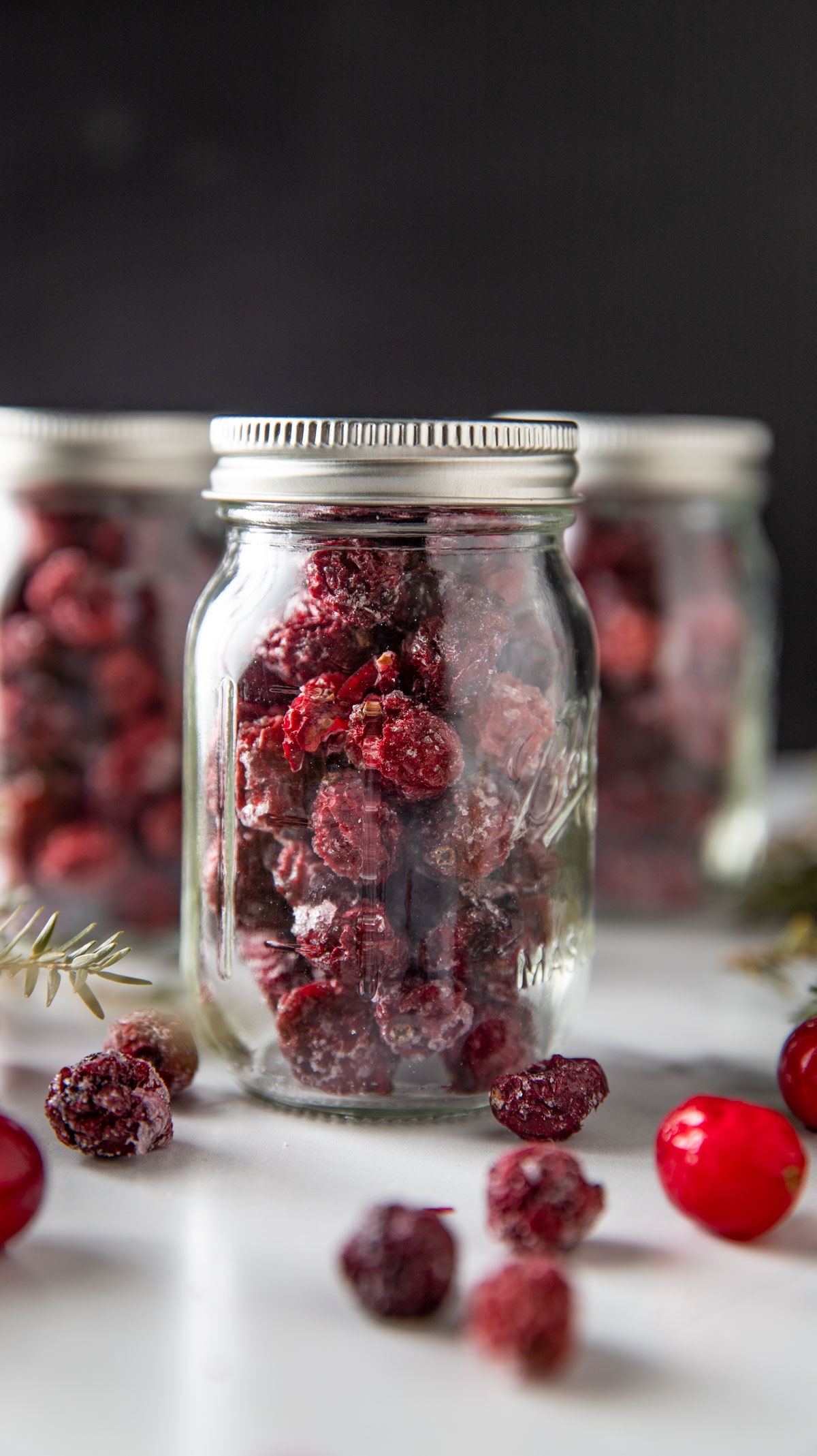 Jars of dried cranberries on white board.