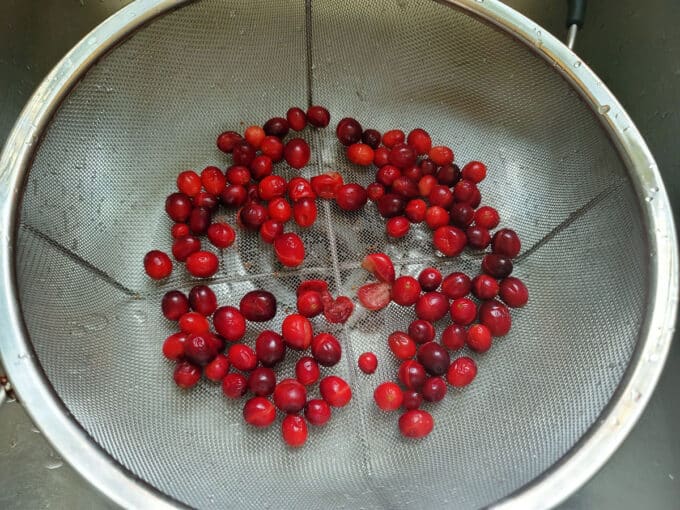 Split cranberries draining in colander.