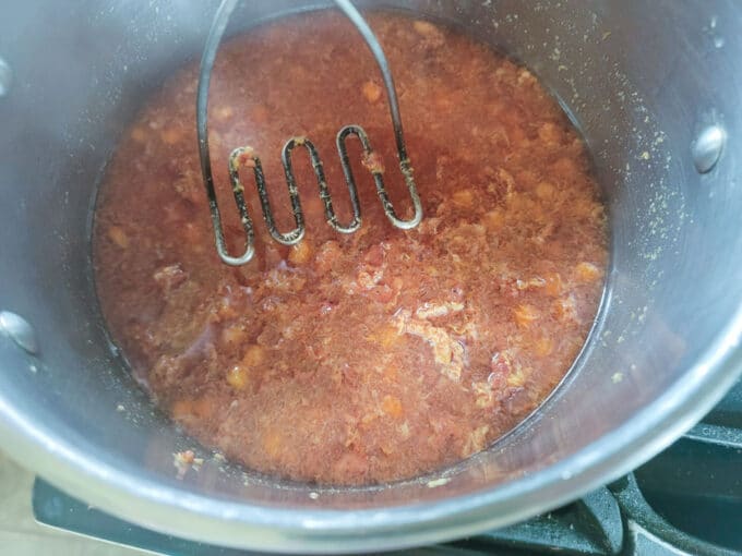 Mashing the fruit with a potato masher.