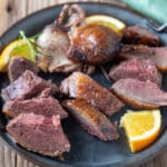 Slice duck meat of pewter plate.