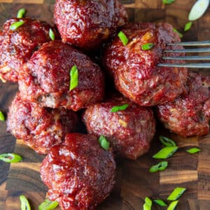 Pile of smoked meatballs on wooden board.