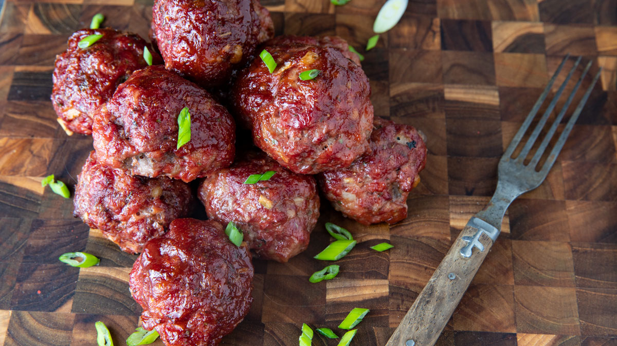 Smoked meatballs in a pile on board with antique fork.