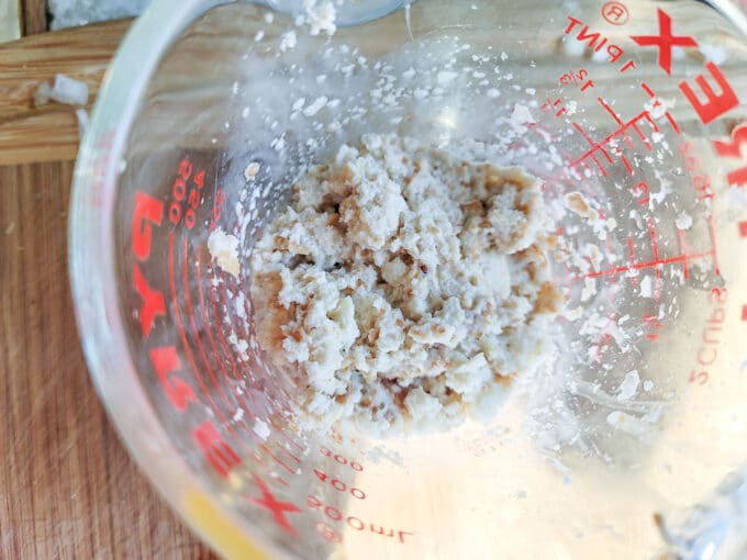 Bread crumbs added to milk in measuring cup.