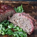 Slices of smoked meatloaf on a bed of greens.