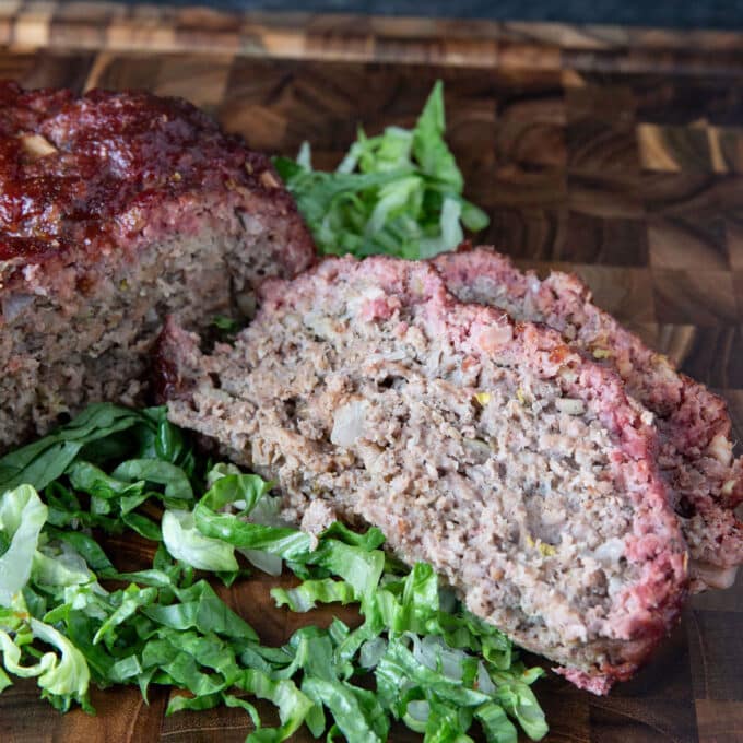 Slices of smoked meatloaf on a bed of greens.