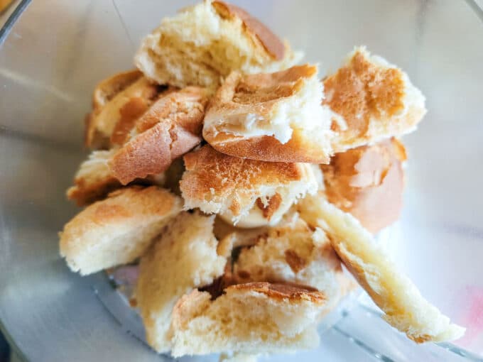 Broken pieces of bread in food processor bowl.