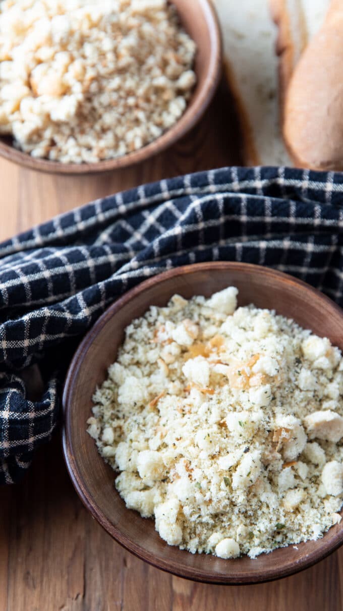 Wooden bowls of bread crumbs with a black and tan checked towel.