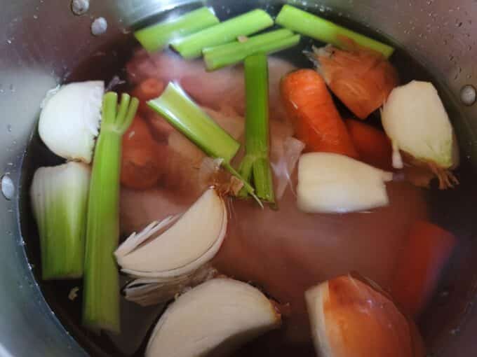 Vegetables added to chicken in pot.