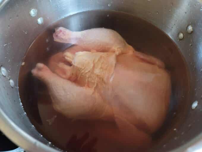 Whole chicken in a large pot, covered with water.