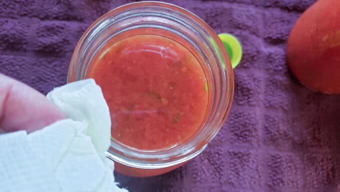 Wiping off rim of jar with paper towel.