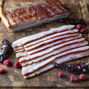 Sliced chipotle bacon on wooden board.